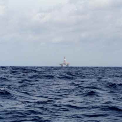 Oil rig being towed by a tug.